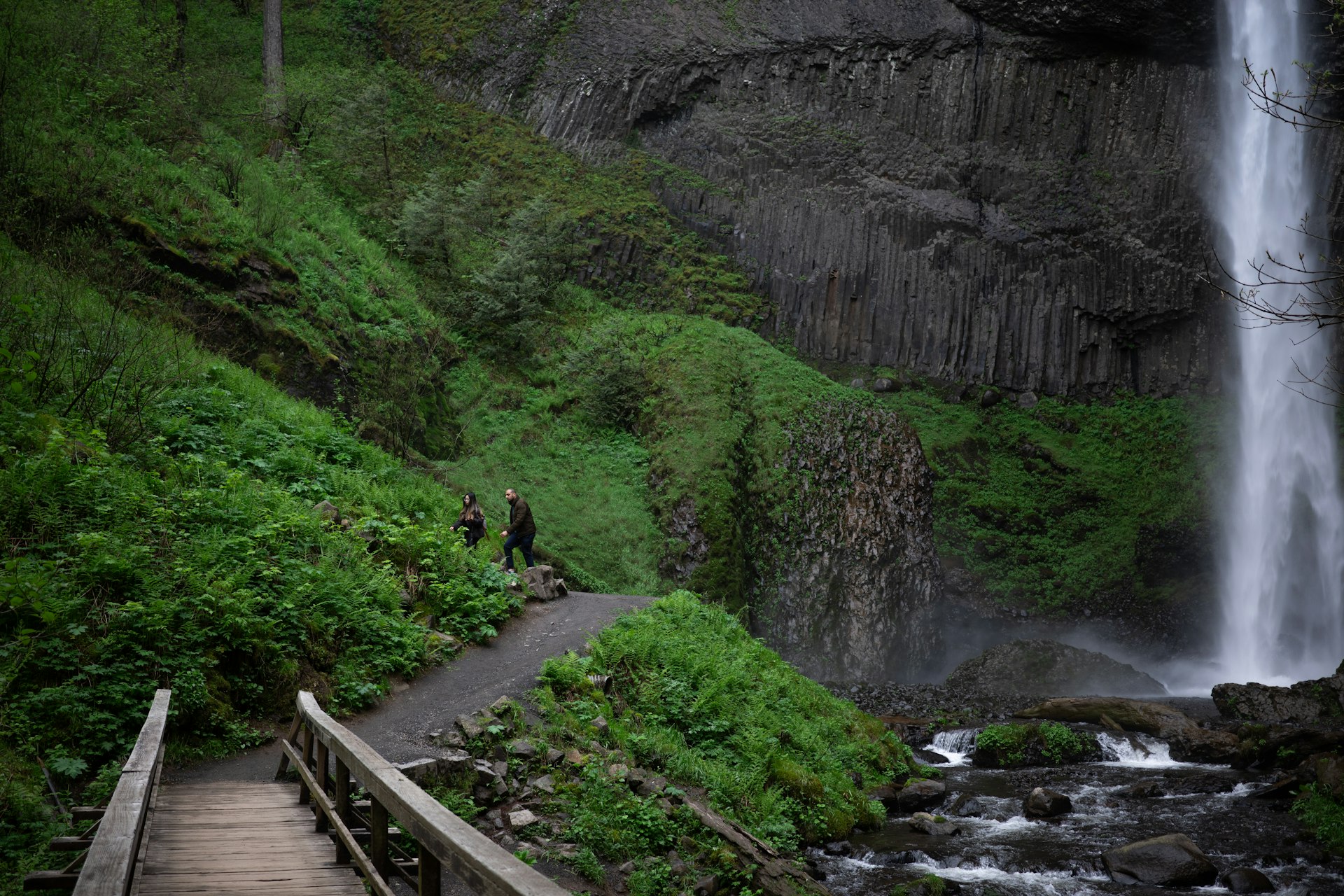 Walkers along a path near a dramatic plunging waterfall