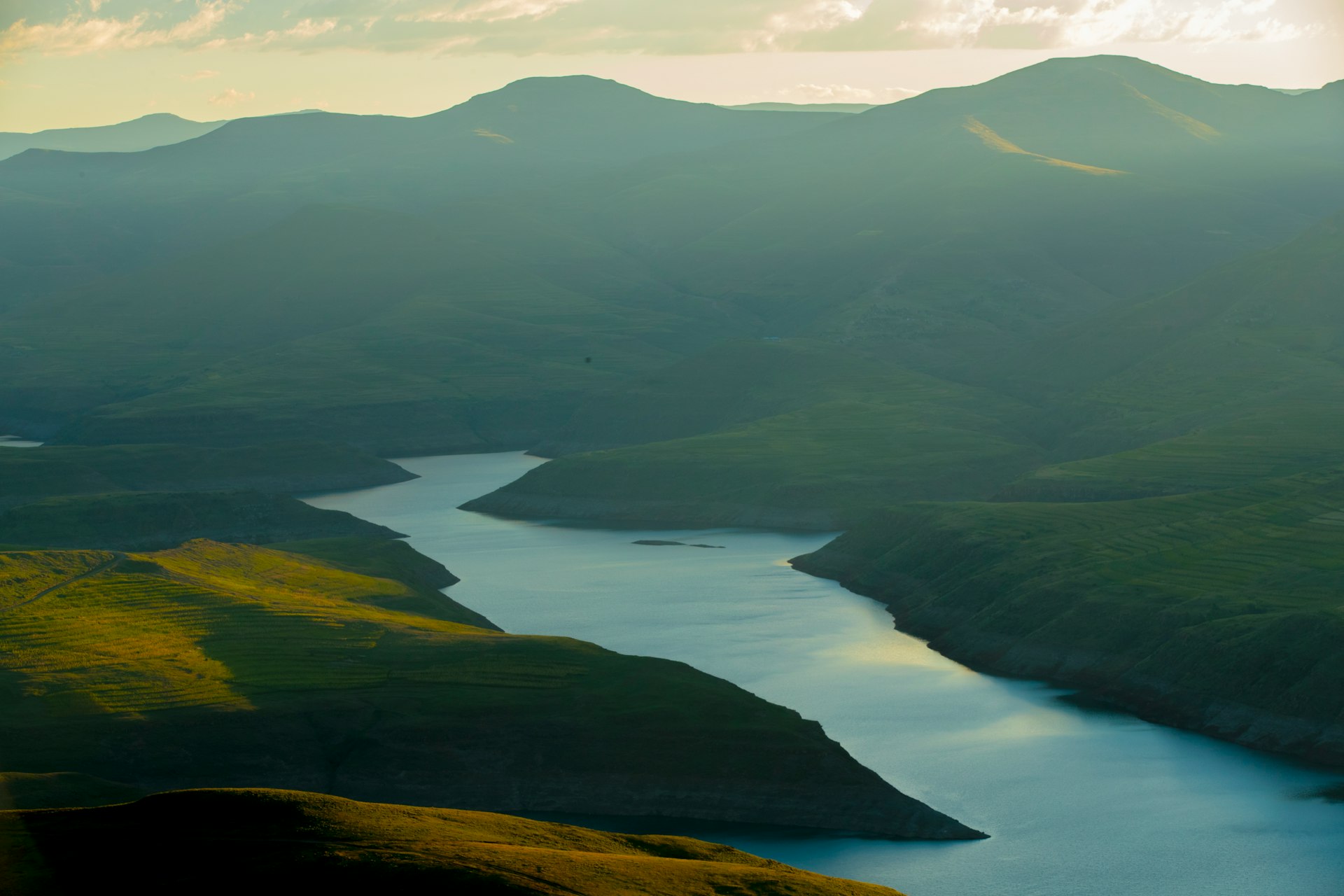 Green Lesotho mountains rising above an alpine lake